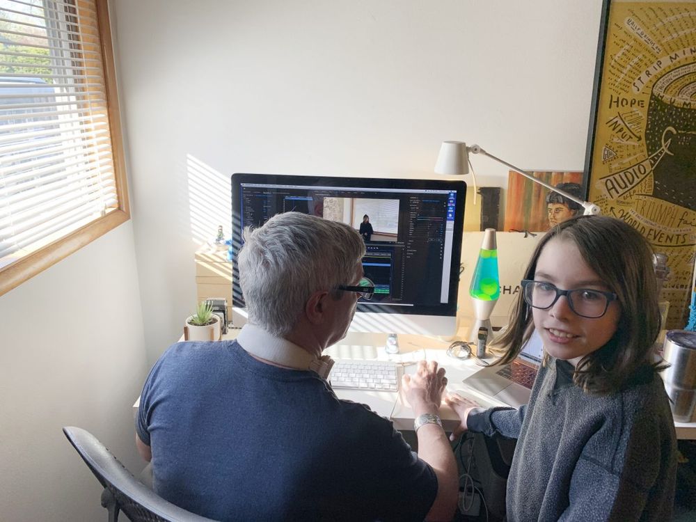 man & child in home office: stacked artwork against the wall helps absorb noise from adjacent rooms